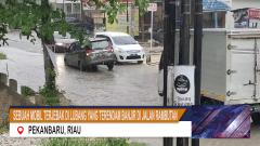 MOBIL SIGRA TERJEBAK DI LUBANG YANG TERENDAM GENANGAN AIR DI JALAN RAMBUTAN